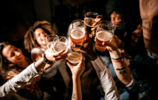 Excited Friends Toasting With Beer Glasses At Pub