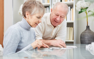 Couple Calculating Bills At Table In House