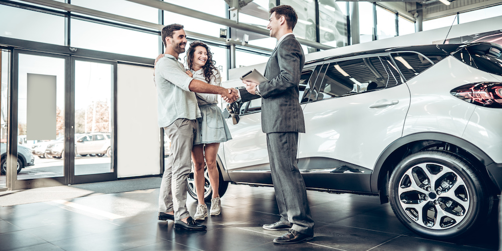 Young Couple Shaking Hands With Sales Agent After A Successful Car Buying