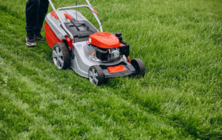 Man Cutting Grass With Lawn Mover In The Back Yard